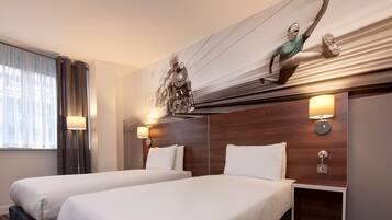 Habitación de hotel con dos camas, un mural grande de un tren y un cabecero de madera.