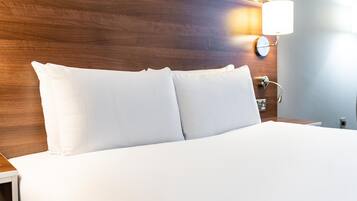 A neatly made bed with white linens in a hotel room.