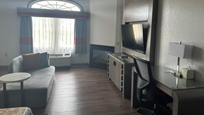 Un salon moderne avec un canapé, une petite table ronde, un téléviseur et une cheminée.