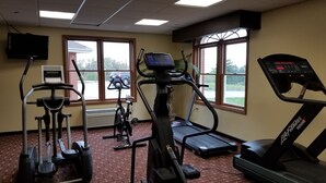 Une salle de sport équipée de tapis de course, d’un vélo elliptique et d’un vélo d’appartement.