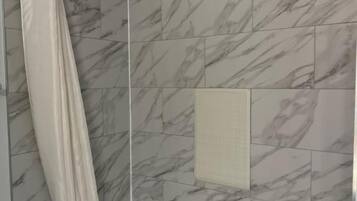 A bathroom with a bathtub, a shower curtain, and marble-patterned tiles.