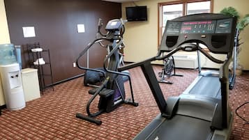 A gym with treadmills, elliptical machines, and a water cooler.