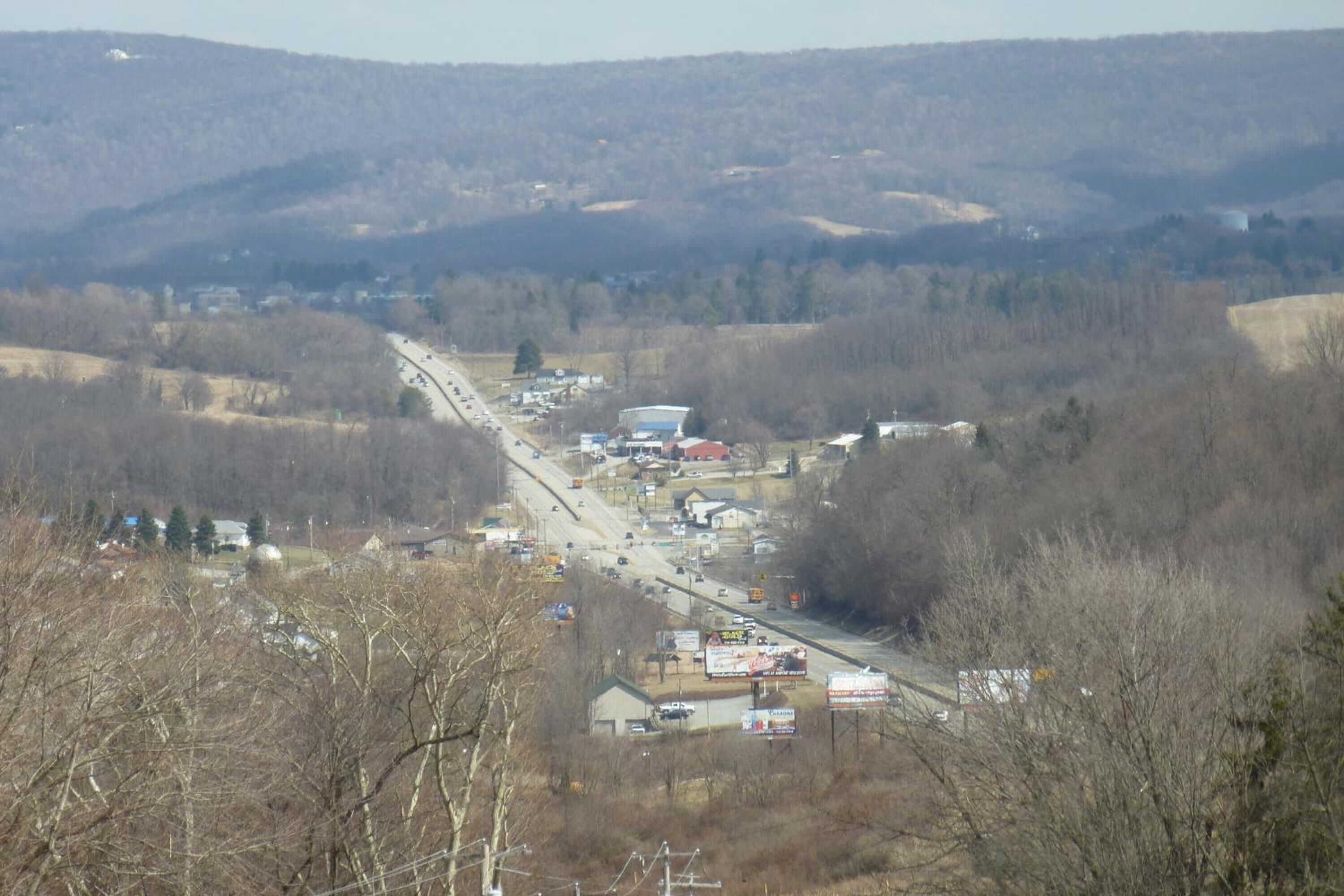 Une ville avec une rue principale, des bâtiments et des collines en arrière-plan.