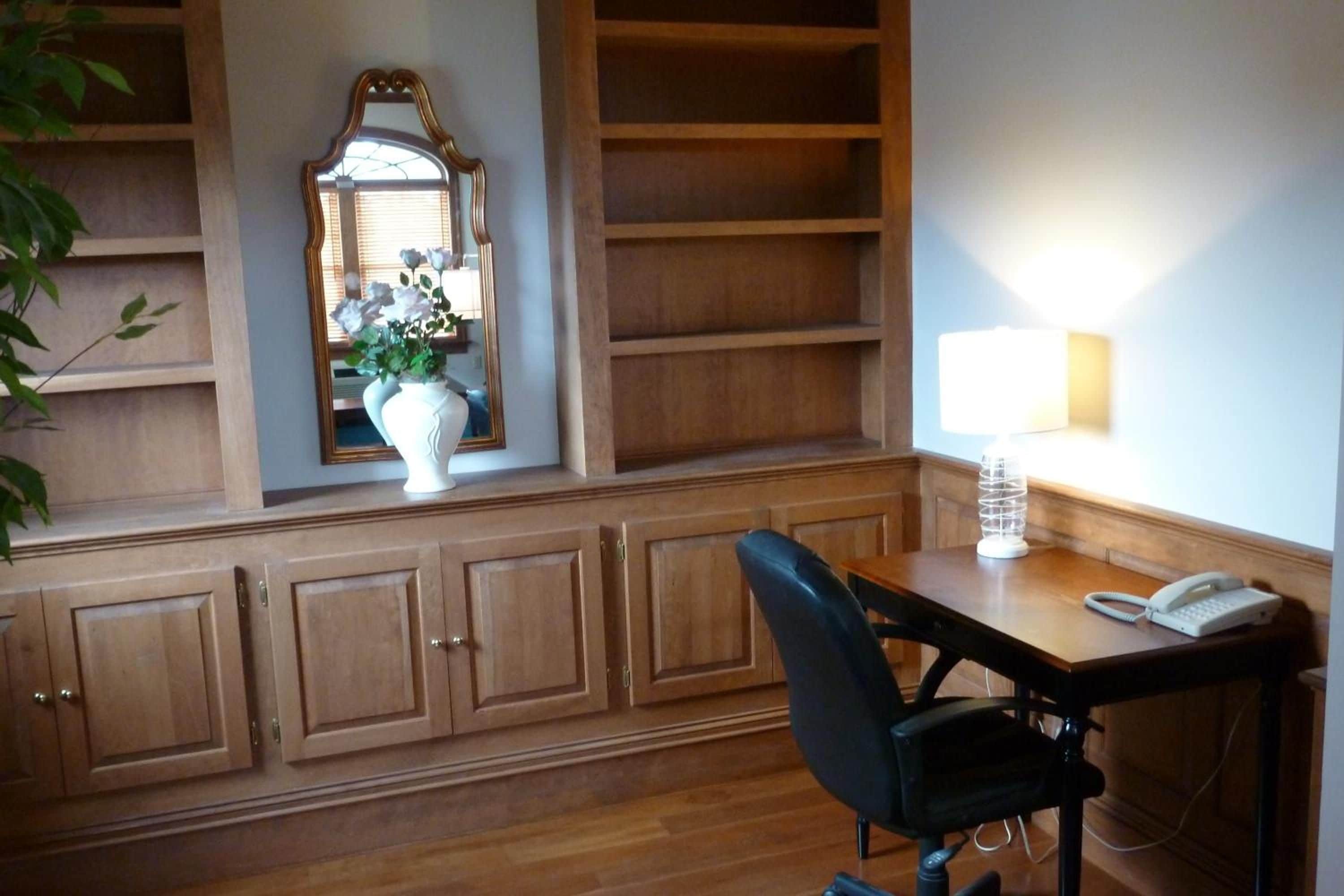 A room with wooden cabinetry, a desk with a telephone, and a chair.