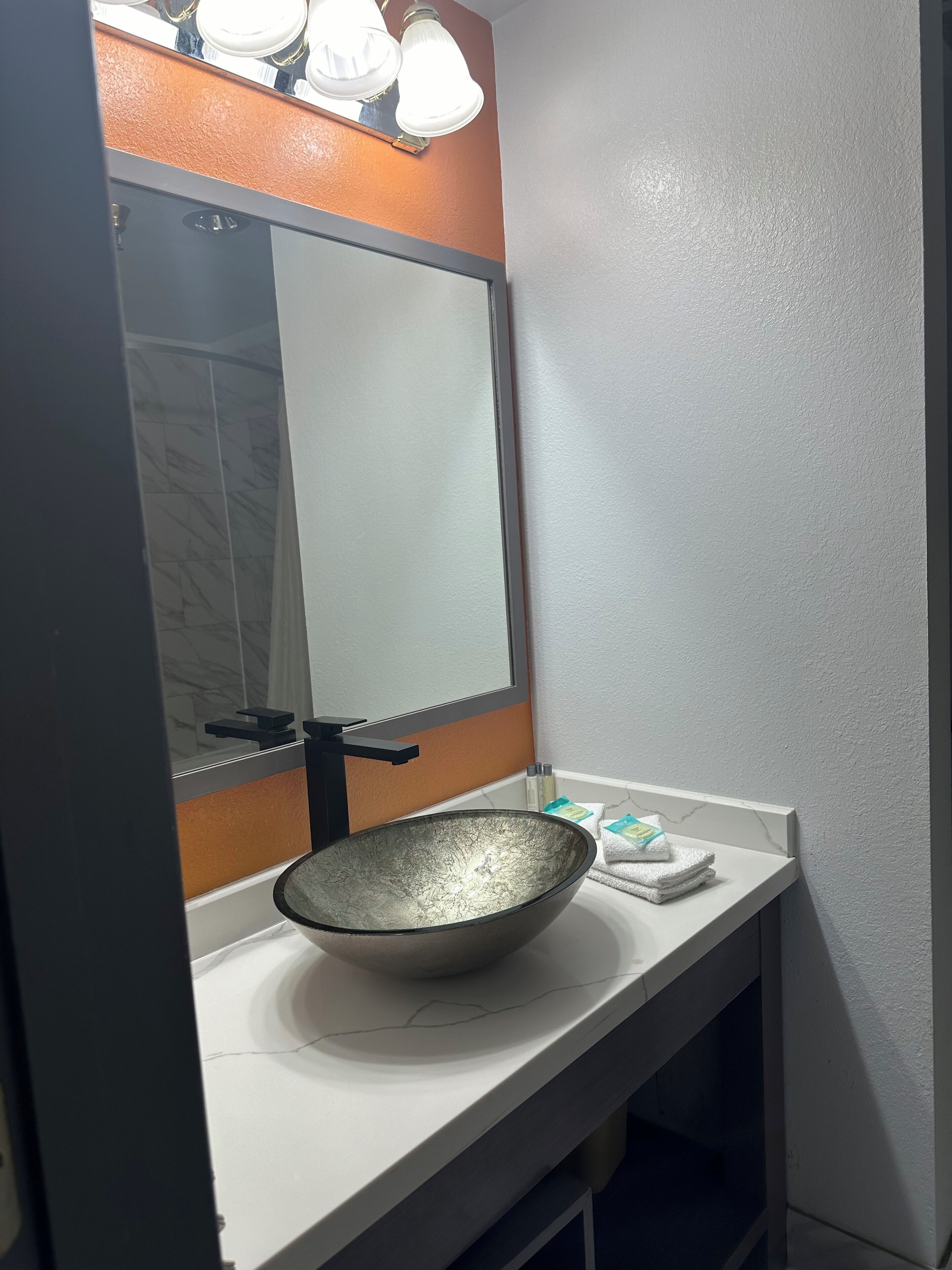 A bathroom with a white sink, a large mirror, and a light fixture above the mirror.