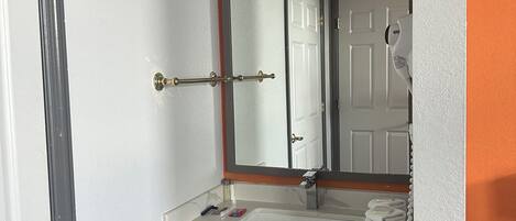 A bathroom with a white sink, a mirror, and an orange accent wall.