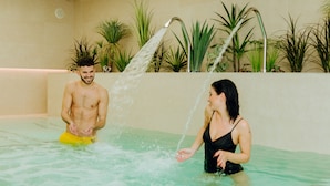 Un homme et une femme dans une piscine avec des jets d’eau.