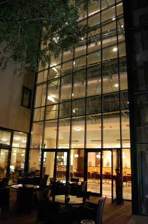 A modern building with a glass facade, interior seating area, and visible structural elements. - Hotel Ginkgo (Hodmezovasarhely)