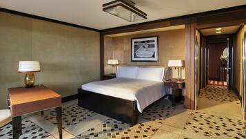 Una habitación de hotel con una cama, dos mesitas de noche con lámparas, un cuadro en la pared y un suelo estampado.
