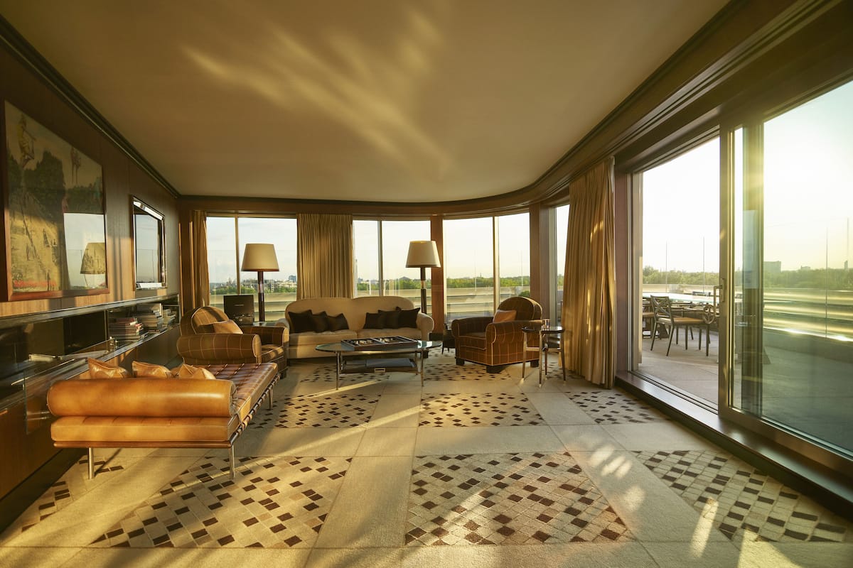 A spacious living room with a large window, a sofa set, a coffee table, and a television.