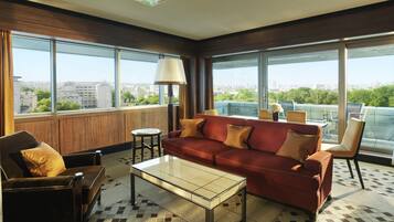 A modern living room with a red sofa, a glass coffee table, and a view of a cityscape through large windows.