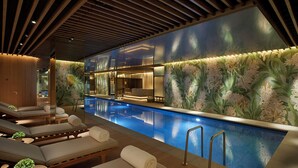 A modern indoor pool area with lounge chairs and a wall mural. - 45 Park Lane - Dorchester Collection (London)