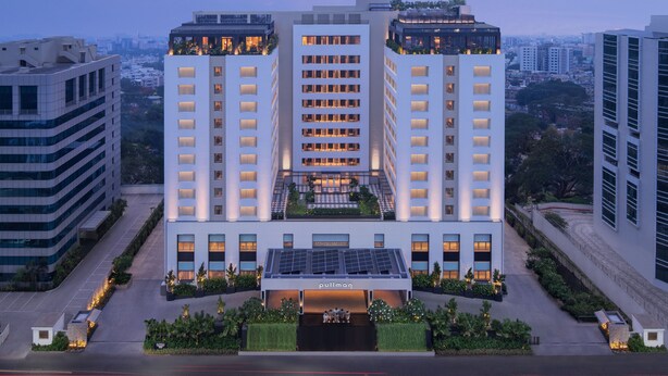 A high-rise hotel with a central atrium, multiple floors, and a rooftop garden. - Pullman Chennai Anna Salai - Premium Brand By Accor (Chennai)