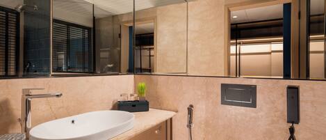A modern bathroom with a large mirror, a sink, a shower, and a toilet.