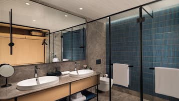 A modern bathroom with two sinks, a large mirror, and a glass shower enclosure.