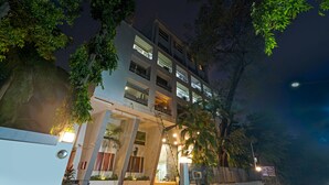 Un hôtel à plusieurs étages, doté d’un design moderne, avec un escalier central, de grandes fenêtres et une entrée bien éclairée.