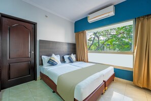 A hotel room with a large bed, a wooden door, a window with curtains, and an air conditioning unit. - asar Landmark Suites Mumbai International Airport by Orion Hotels (Mumbai)