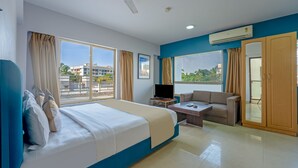 A hotel room with a bed, a TV, a sofa, and a desk. - asar Landmark Suites Mumbai International Airport by Orion Hotels (Mumbai)