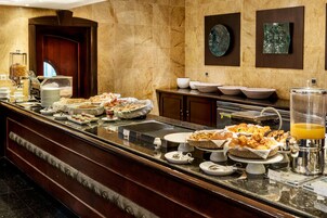 Un bufé con diversas opciones de comida y un dispensador de zumo.