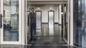 Un moderno vestíbulo de hotel con suelo mojado, puertas de vidrio y ascensores.