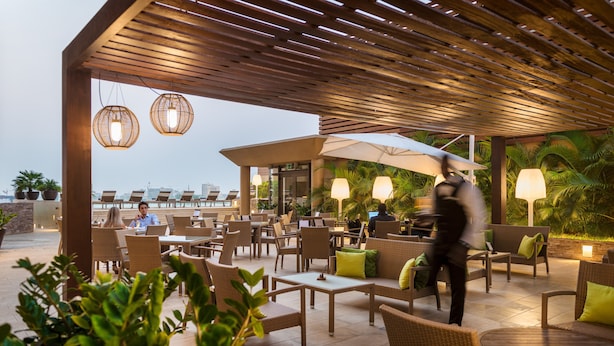 Un patio al aire libre con mobiliario de mimbre, sombrillas y plantas en macetas.