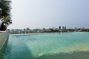 Una piscina infinita en la azotea con vista al horizonte de la ciudad.