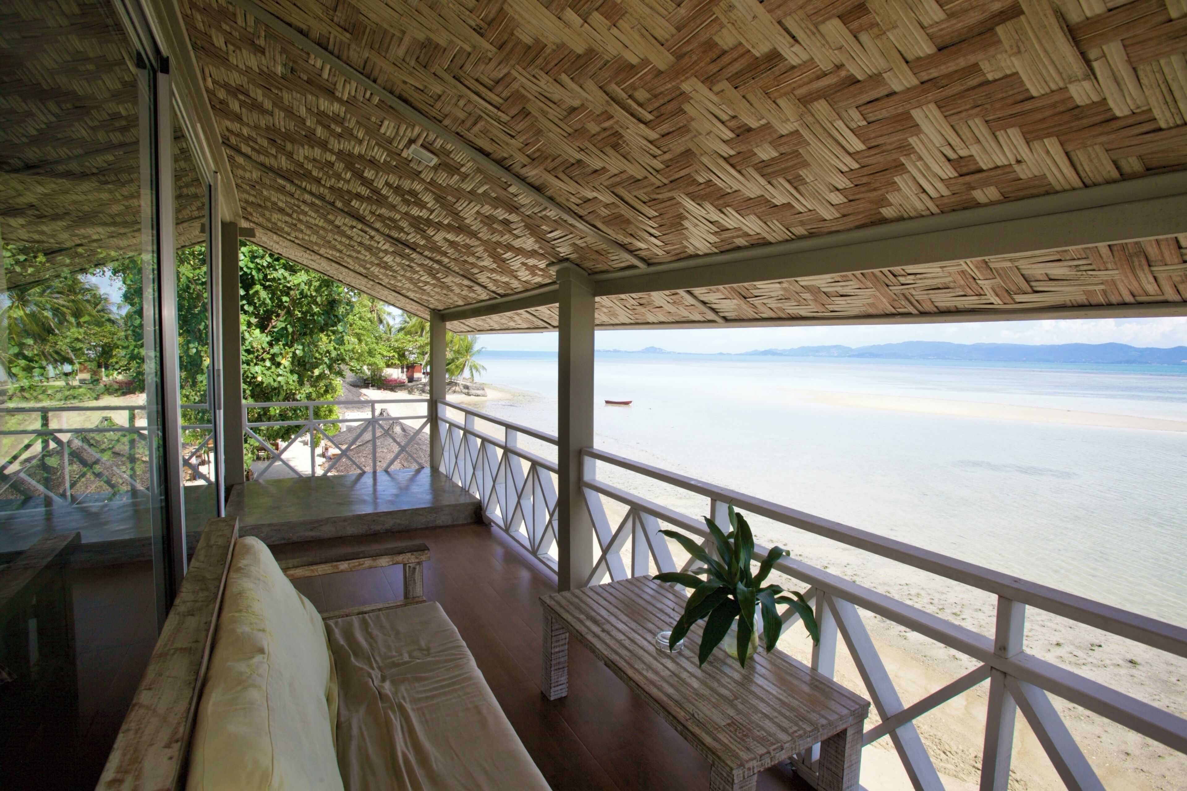A covered outdoor seating area with a view of the beach and ocean.