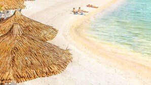 A beach with thatched umbrellas, palm trees, and a clear blue sea. - Milky Bay Resort (Ko Pha-ngan)