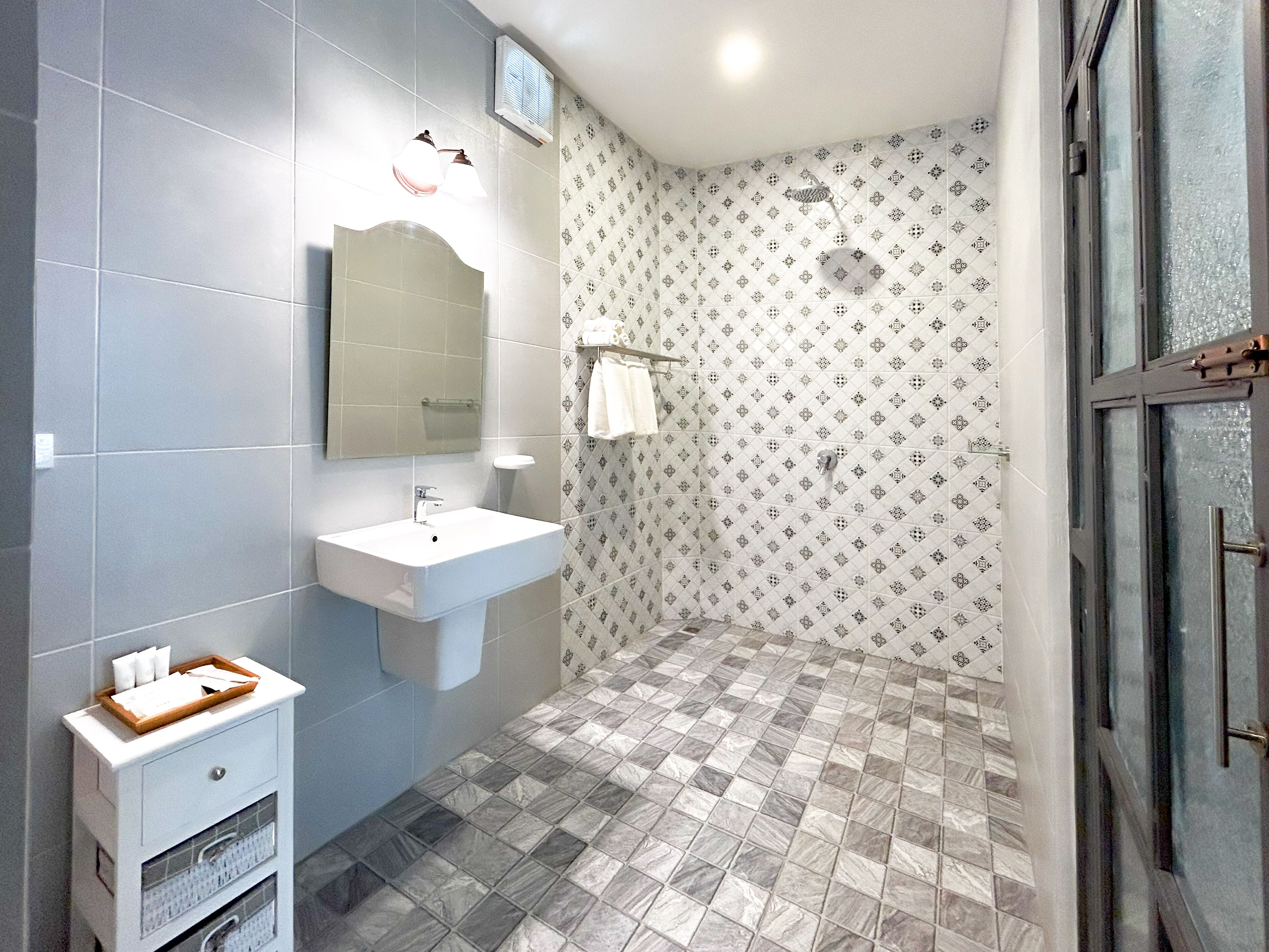 A bathroom with a sink, mirror, and shower.