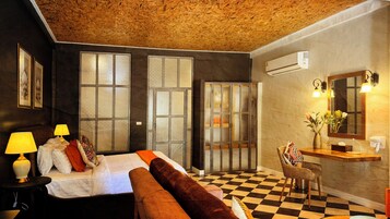 A room with a bed, two lamps, a chair, a mirror, and an air conditioning unit.