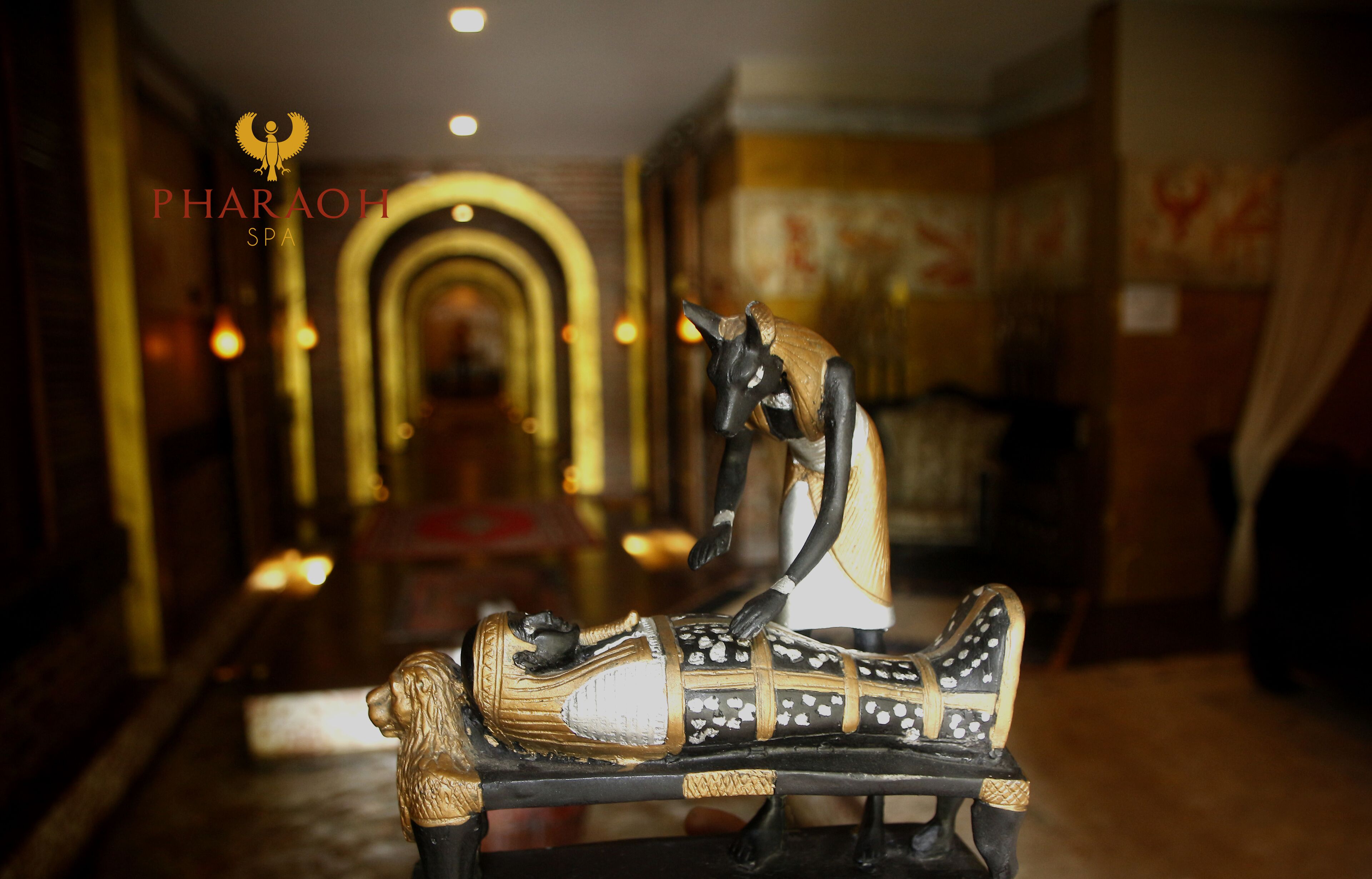 A statue of a reclining figure in a chair, with a logo reading "PHARAOH SPA" in the background.