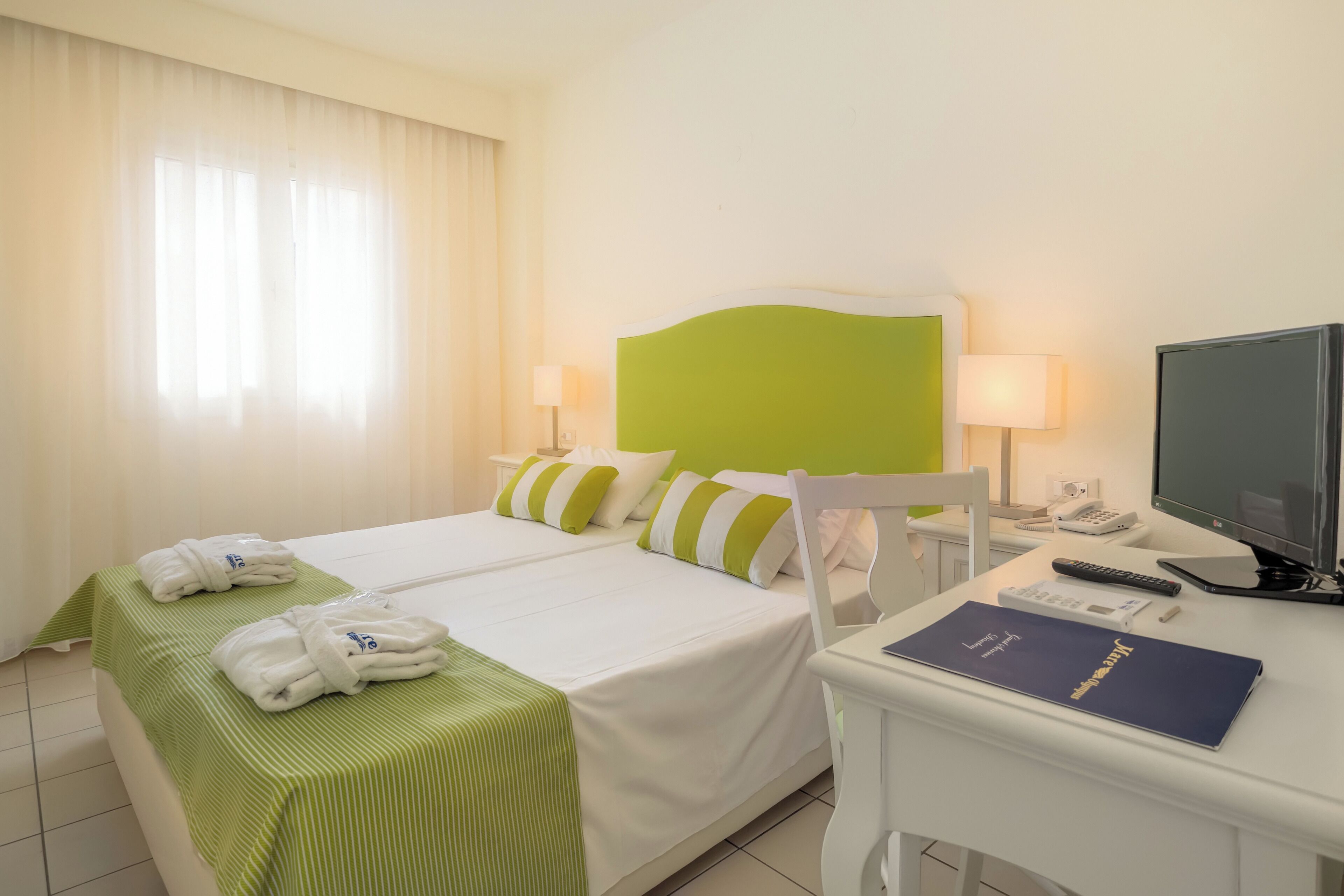 Una habitación de hotel con dos camas, un escritorio, un televisor y una lámpara.