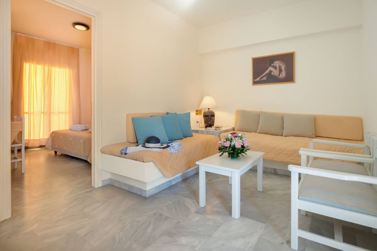 Ein modernes Schlafzimmer mit einem Bett, einem Schlafsofa, einem kleinen Tisch und einem Sessel.