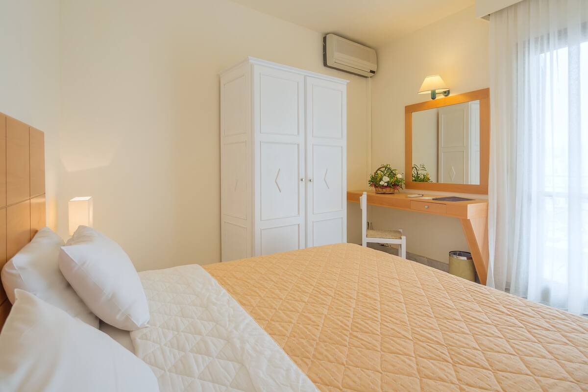 Ein Hotelzimmer mit Bett, Schrank, Schreibtisch und Spiegel.