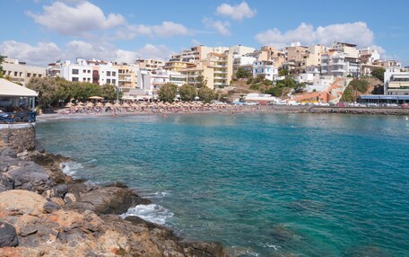 A coastal town with a beach, buildings, and rocky shoreline.
