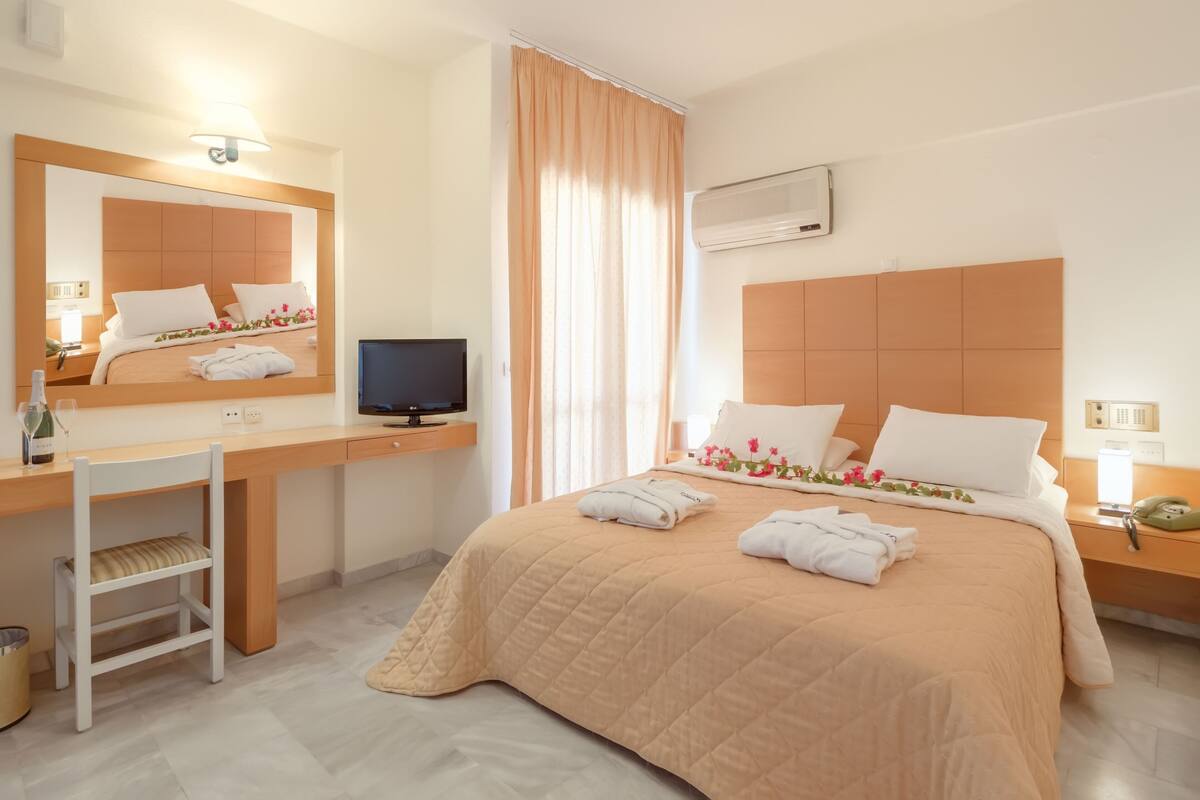 Ein Hotelzimmer mit Bett, Schreibtisch, Stuhl, Fernseher und einem Badebereich.
