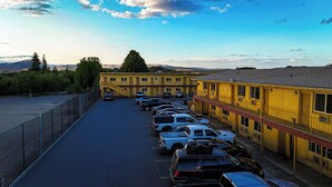 A parking lot with multiple cars parked in front of a yellow building with a red roof.