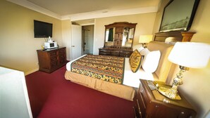 A hotel room with a bed, dresser, television, and a mirror.