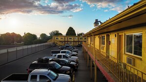 A parking lot with multiple cars parked in front of a yellow building with a red awning.