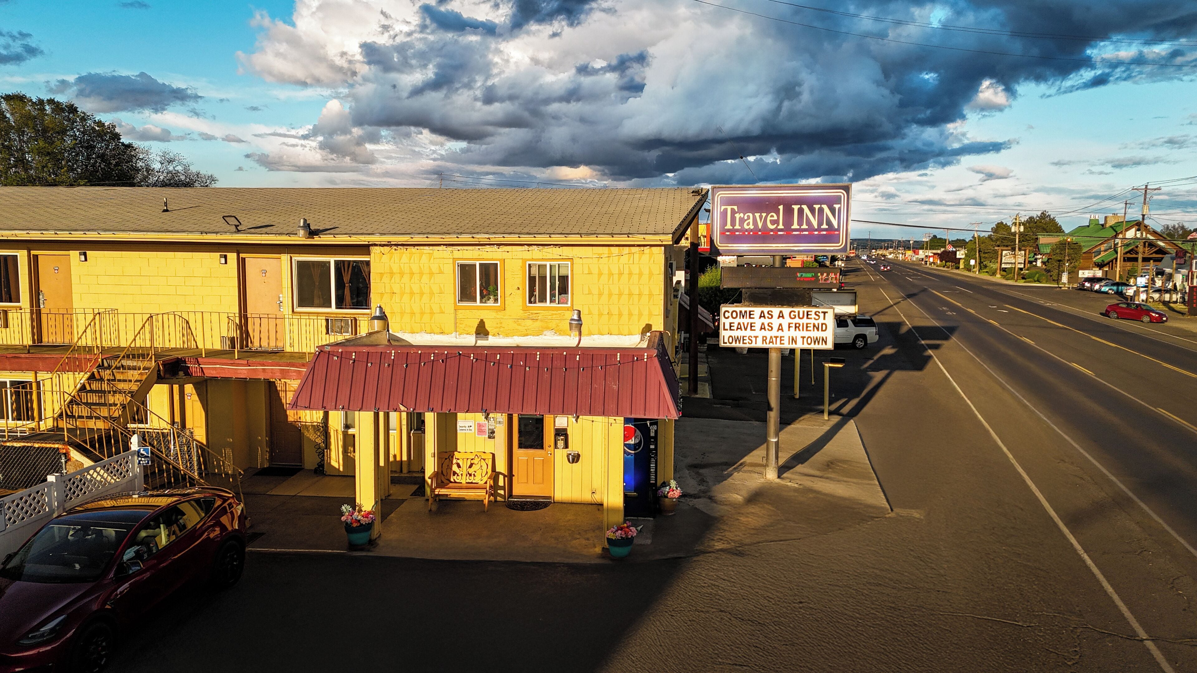 A Travel Inn with a red awning, a sign advertising the lowest rate in town, and a clear view of the street.