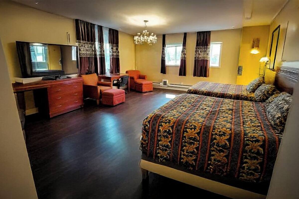 A bedroom with a large bed, a desk, a chair, and a TV.