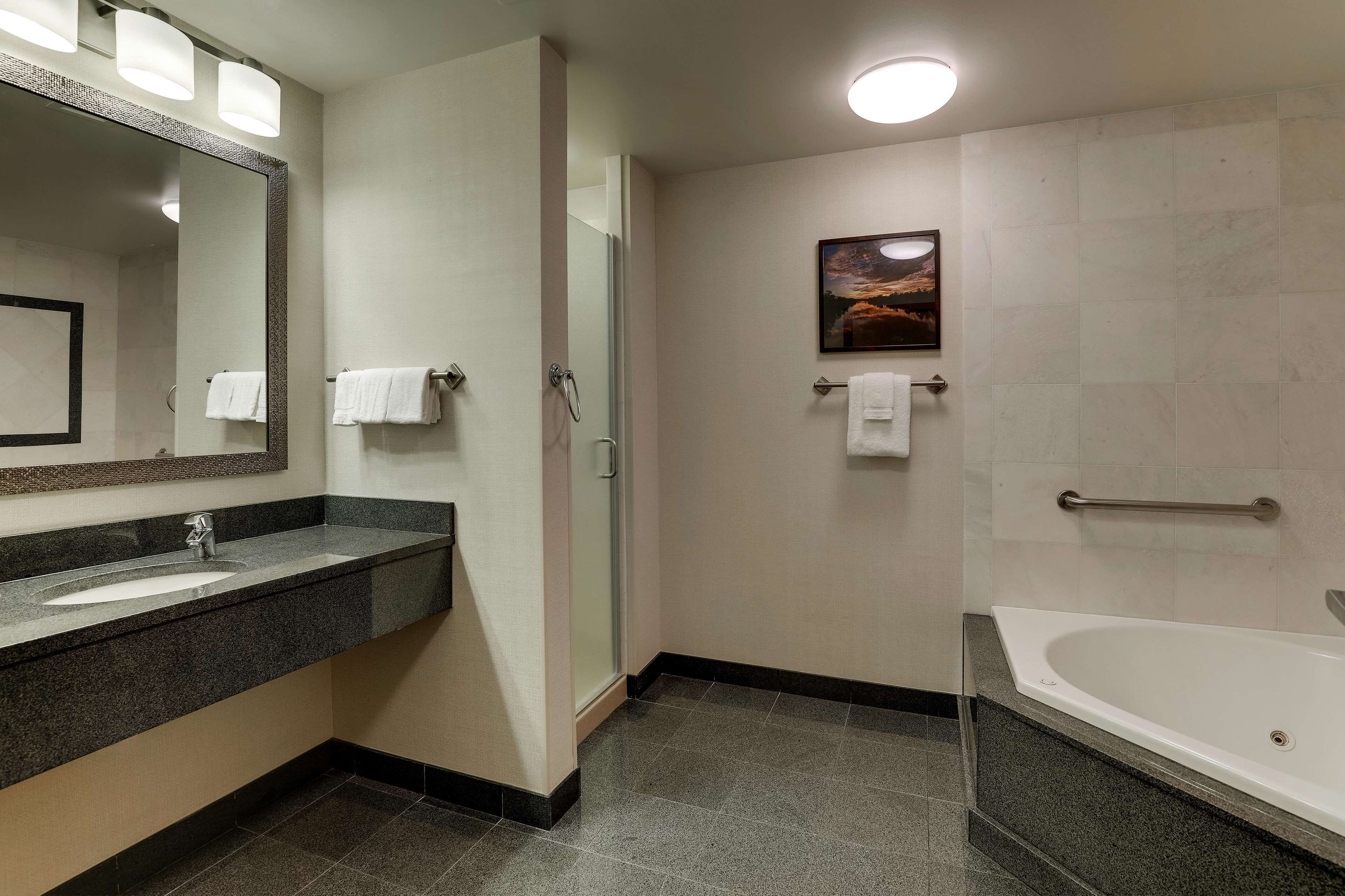 A modern bathroom with a large mirror, a sink, a shower, and a bathtub.