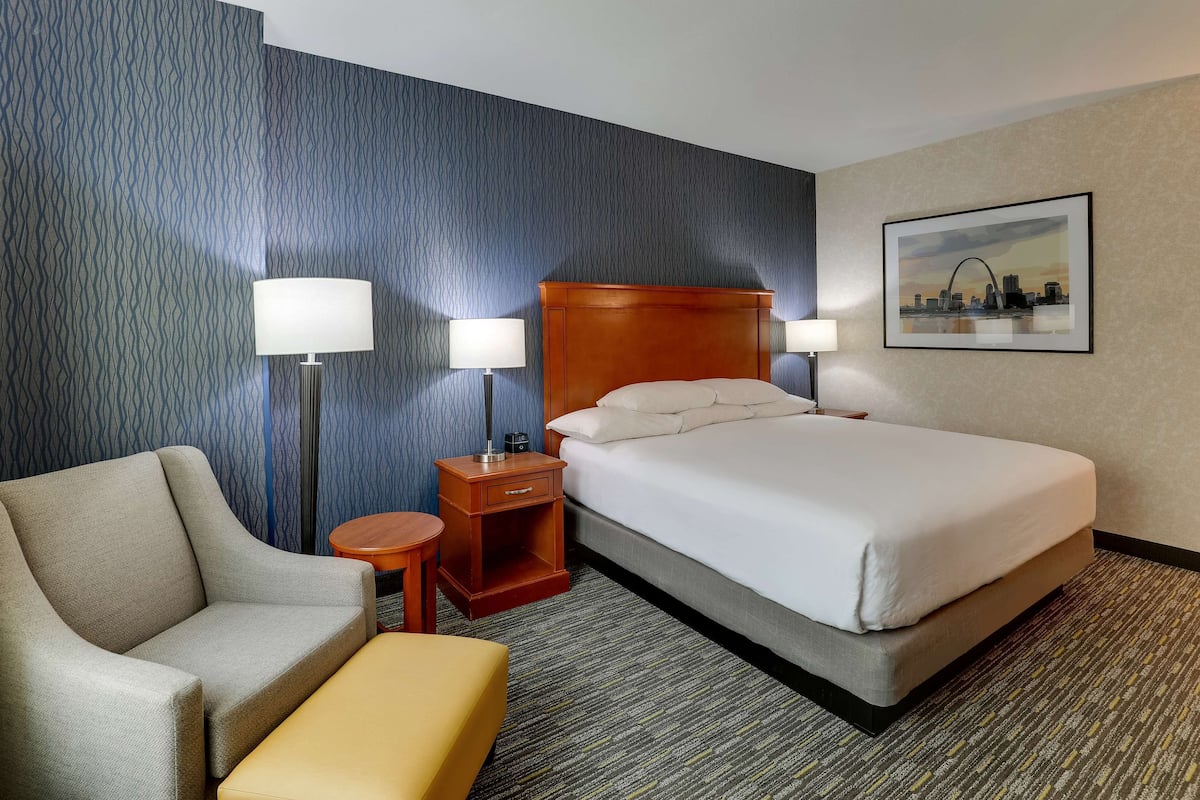 Una habitación de hotel con cama, sofá, una mesita y dos lámparas.