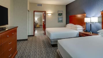 Una habitación de hotel con dos camas, televisión, escritorio y lámpara.