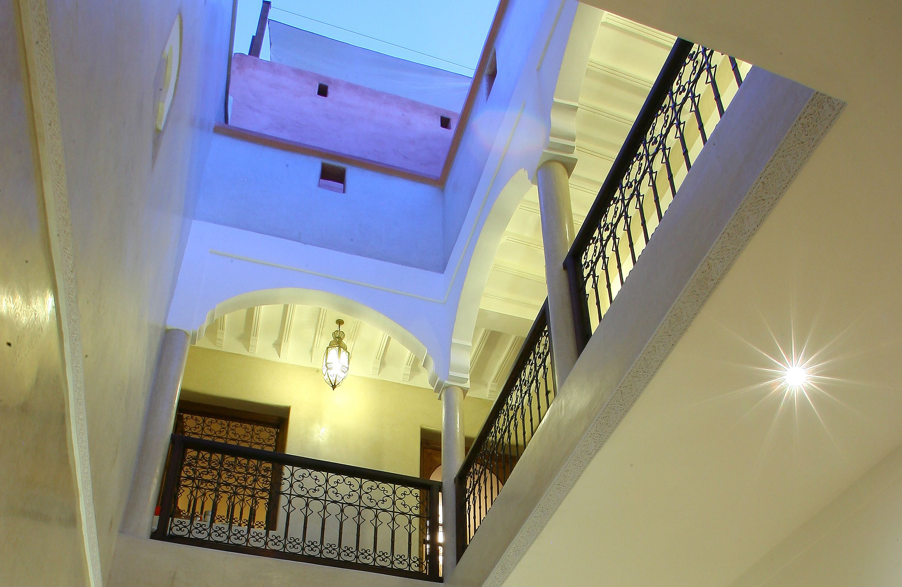 A multi-level interior with a staircase, a balcony, and a decorative light fixture.