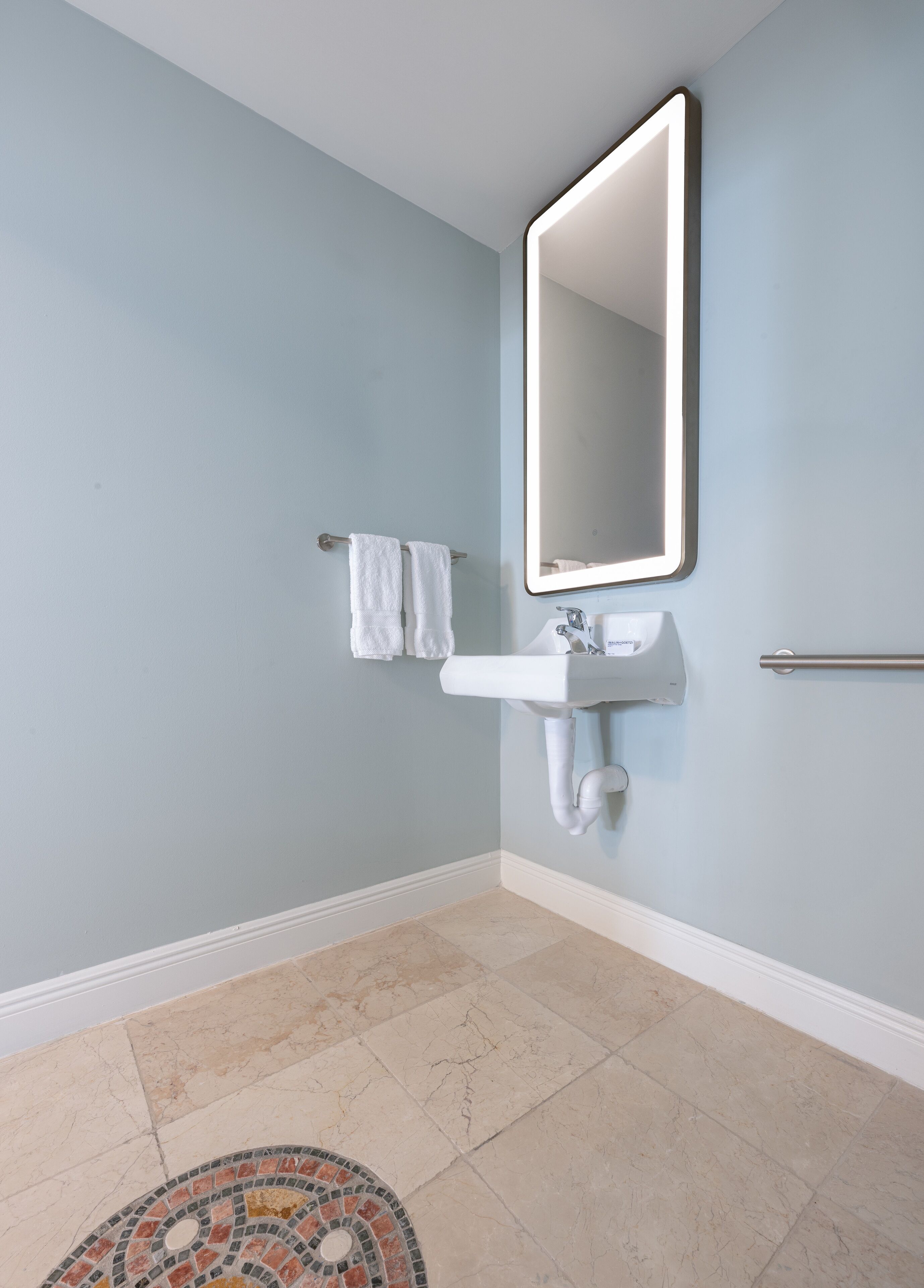 Une salle de bain avec un lavabo blanc, un miroir et un porte-serviettes.