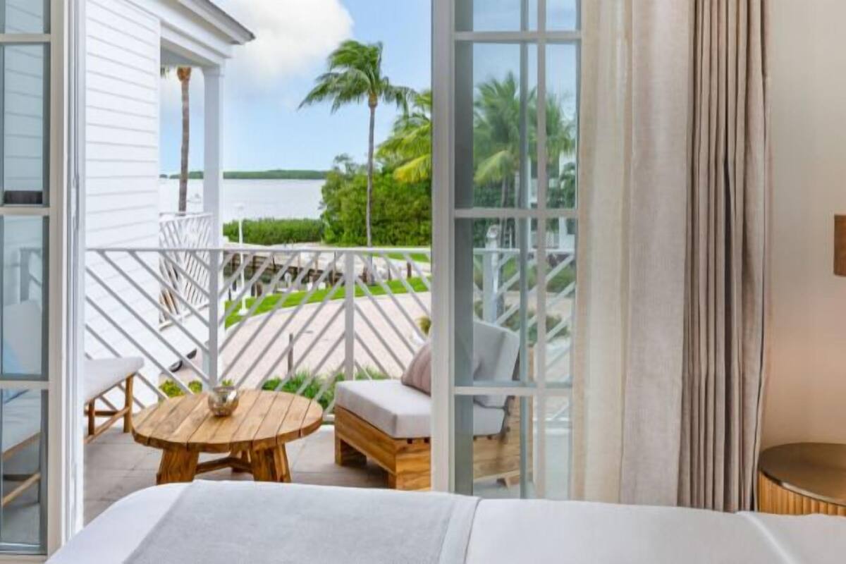 A bedroom with a view of a balcony, a wooden table, and a sofa.