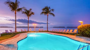 Una piscina al aire libre, sombrillas, sillones reclinables de piscina