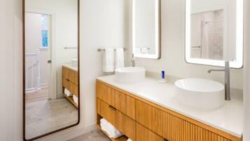 Un baño moderno con dos lavamanos, tocador de madera y un espejo grande.