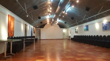 A spacious hall with a high ceiling, rows of chairs, and artwork on the walls.